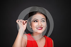 Make-up and cosmetics concept. Asian woman doing her makeup eyelashes black mascara.