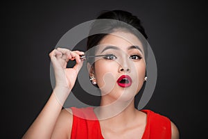 Make-up and cosmetics concept. Asian woman doing her makeup eyelashes black mascara.