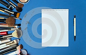 Make up the essentials. A set of professional makeup brushes and cosmetics on a blue background