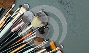 Make up the essentials. A set of professional makeup brushes and cosmetics on a gray background.