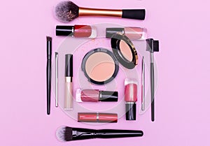 Make up the essentials. A set of professional makeup brushes and cosmetics on a pink background.