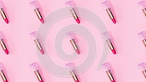 Make up pattern made of pink lipsticks rotate on bright pink background. Stop motion