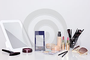 Make-up products with mirror on dressing table. Vanity table with makeup accessories