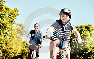 Make way for the biker boys. a young boy and his father riding together on their bicycles.