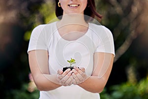 Make way for a greener world. an unrecognisable woman holding a plant growing out of soil.