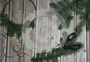 Make a wreath on the door of spruce branches and willow twigs. Scissors and hemp rope on a wooden background. Christmas, winter,