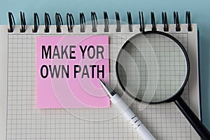 MAKE YOR OWN PATH - words in notepad with magnifying glass and pen