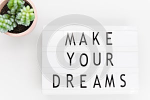 Make your dreams, text written on a lightbox. Decorated with cactus