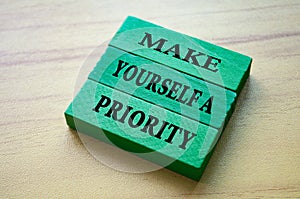 Make yourself a priority text on green color wooden blocks. Aspiration quote.