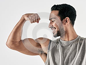 Make yourself proud over and over again. Studio shot of a muscular young man flexing his biceps against a white