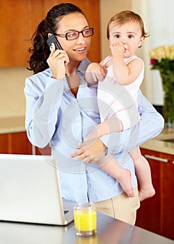 She makes balancing work and home look easy. a happy-looking single mom talking on the phone while cradling her baby.