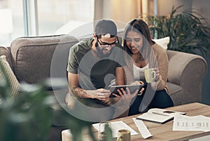 It makes good cents to budget with smart apps. a young couple sing a digital tablet while going through paperwork at