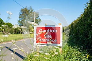 Makeshift Site Entrance sign seen located  on a grassy verge, near a village.