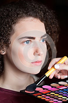 Makeup Applying closeup. Cosmetic Powder Brush. Portrait of beautiful woman getting professional make-up