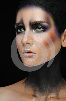 Makeup art and beautiful model theme: beautiful girl with a creative make-up black-and-purple and gold colors on a black backgroun