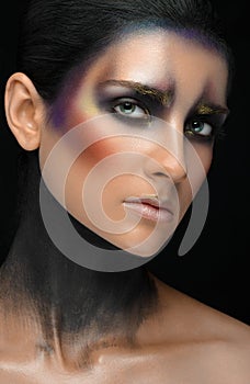 Makeup art and beautiful model theme: beautiful girl with a creative make-up black-and-purple and gold colors on a black backgroun