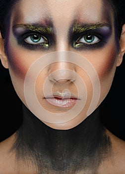 Makeup art and beautiful model theme: beautiful girl with a creative make-up black-and-purple and gold colors on a black backgroun