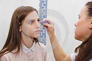 Makeup artist aligns tonal crem on the face of the model