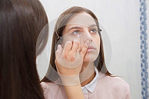 Makeup artist aligns tonal crem on the face of the model