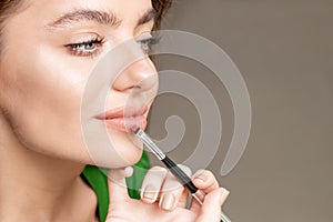 Makeup artist applies lipstick on lips