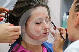 Makeup artist apply makeup on the eyes of young woman. Professional makeup artist applying makeup for bride.