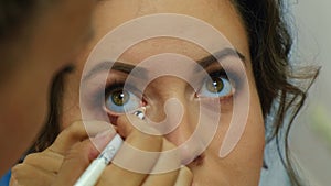 Makeup artist apply makeup on the eyes of young woman. Professional makeup artist applying makeup for bride. Weeding