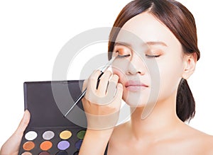 Makeup artist applying colorful eyeshadow on model's eye with a