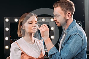 Handsome makeup artist applying eye shadow