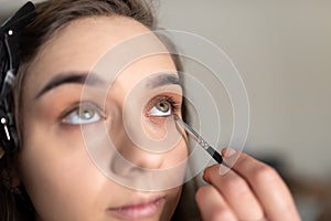 Makeup artist applying eye shadow to the lower eyelid of a girl with a brush