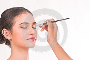 Makeup artist applying eyeshadow for beautiful woman on white background