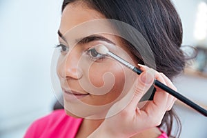 Makeup artist applying eyeshadow to attractive woman