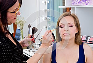 Makeup artist applying eyeshadow on womans eyes