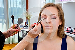 Makeup artist applying eyeshadow on womans eyes