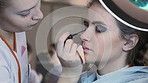 Makeup artist applying false eyelashes to model`s eyes.