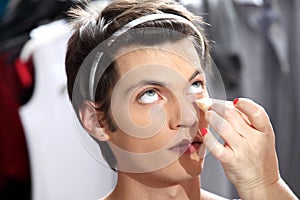 makeup artist applying foundation with a sponge, man in the dressing room mirror photo