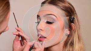 Makeup artist applying makeup on pretty woman face