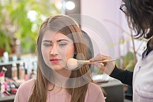 Makeup artist applying makeup to model in salon