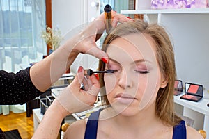 Makeup artist applying mascara on womans eyes