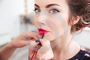 Makeup artist applying pink lipstick to lips of woman