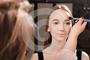 Makeup artist applying a powder on a forehead of a model