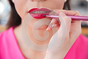 Makeup artist applying red lipstick to lips of woman