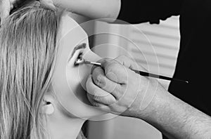 Makeup artist applying shadows on woman eyes