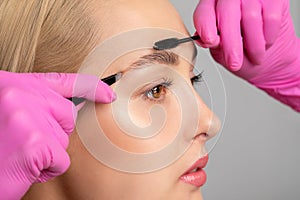 Makeup artist combs  and plucks eyebrows after dyeing in a beauty salon.Professional makeup and cosmetology skin care