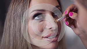 Makeup artist contouring model's nose using a brush