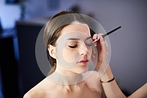 Makeup artist doing perfect make up for the young model in photo studio