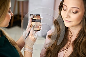 Makeup artist doing professional eye makeup for woman.