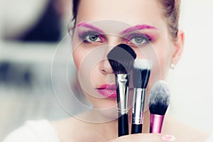 The makeup artist holds powder brushes