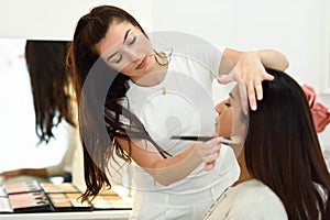 Makeup artist making up an African young woman in a beauty center