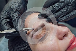 A makeup artist pinches the eyebrows of a woman