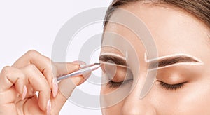 Makeup artist plucks  eyebrows in a beauty salon. Professional make-up and cosmetic skin care